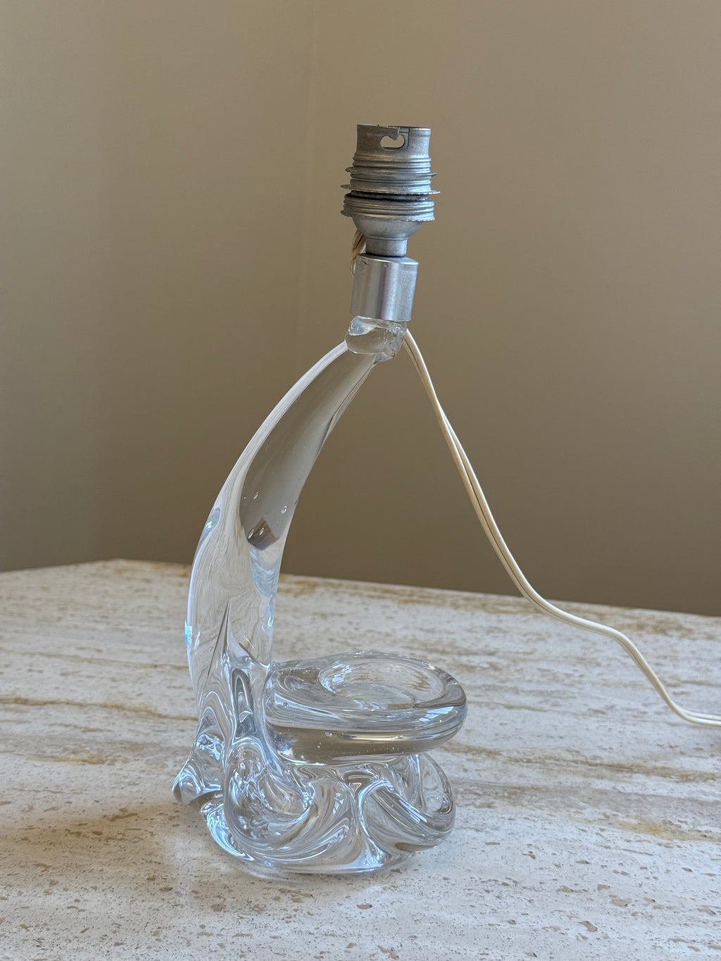 Glass table lamp without a shade on a stone surface with cream background