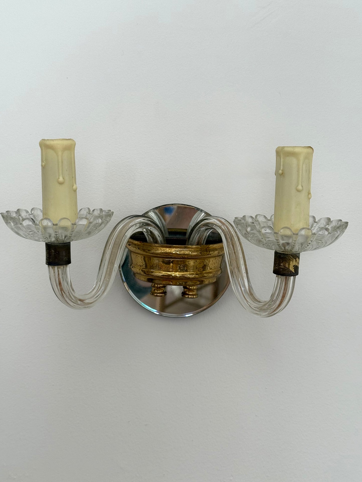 Wall-mounted sconce with two candle-like lights on a plain wall.
