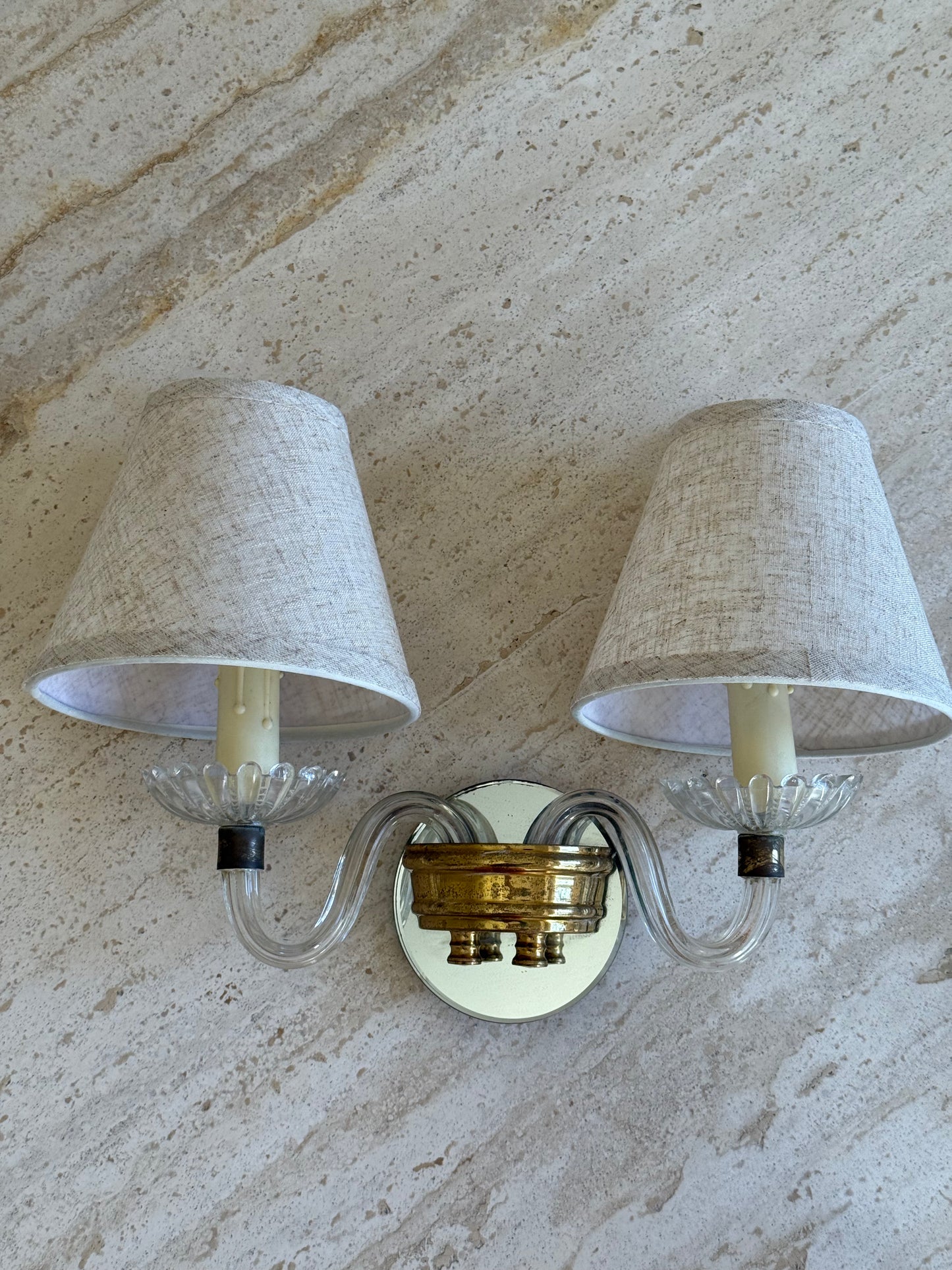 Wall sconce with two lampshades on a textured wall background