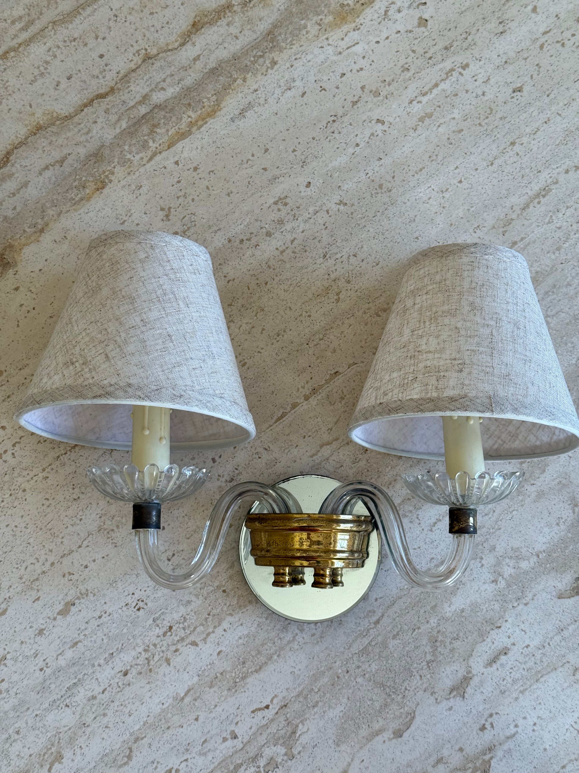 Wall sconce with two lampshades on a textured wall background