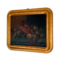 A framed still life oil painting depicting a cluster of red apples, purple grapes, and a pomegranate on a dark background, housed in a wide, ornate gilded gold frame.