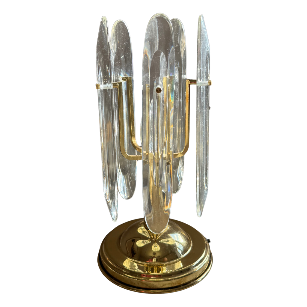 A vintage-style brass and clear glass candelabra with multiple vertical clear glass shades and a round polished brass base, shown against a plain white background.