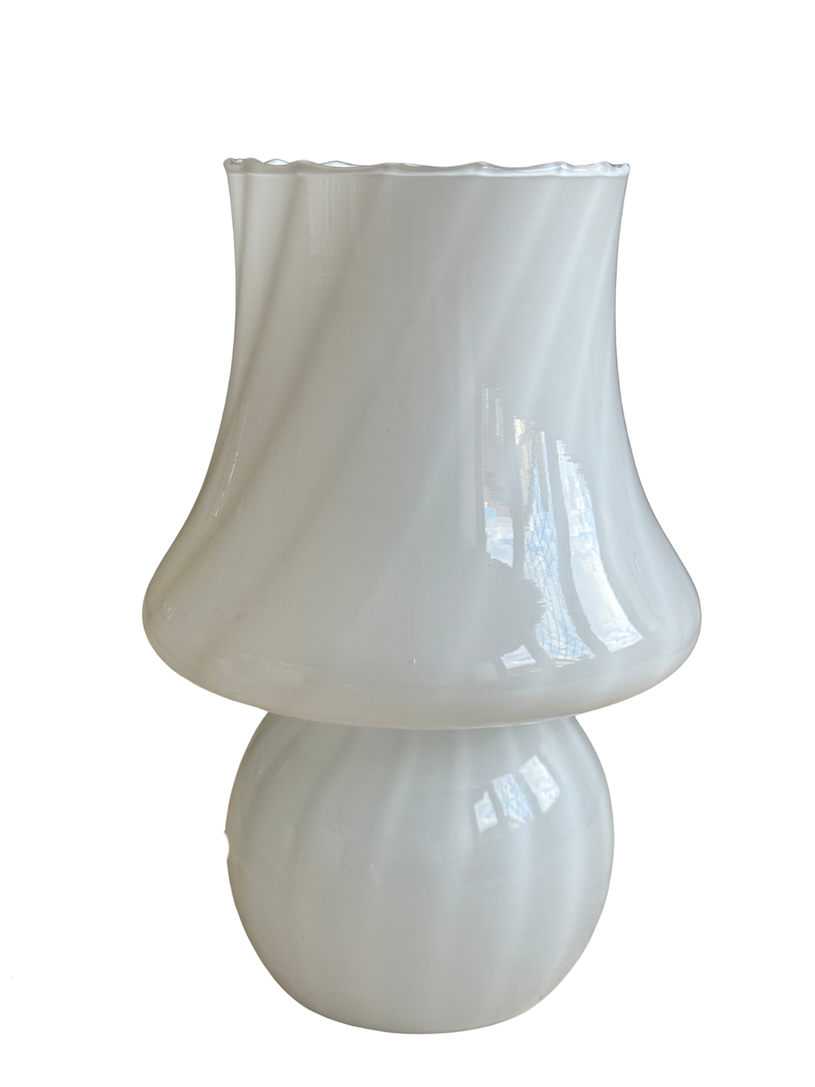 A white glass table lamp with a flared, scalloped shade and a rounded base, shown on a plain white background.