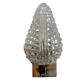 A decorative clear glass wall sconce with an intricate, openwork leaf or tree-like silhouette mounted on a polished metallic base.