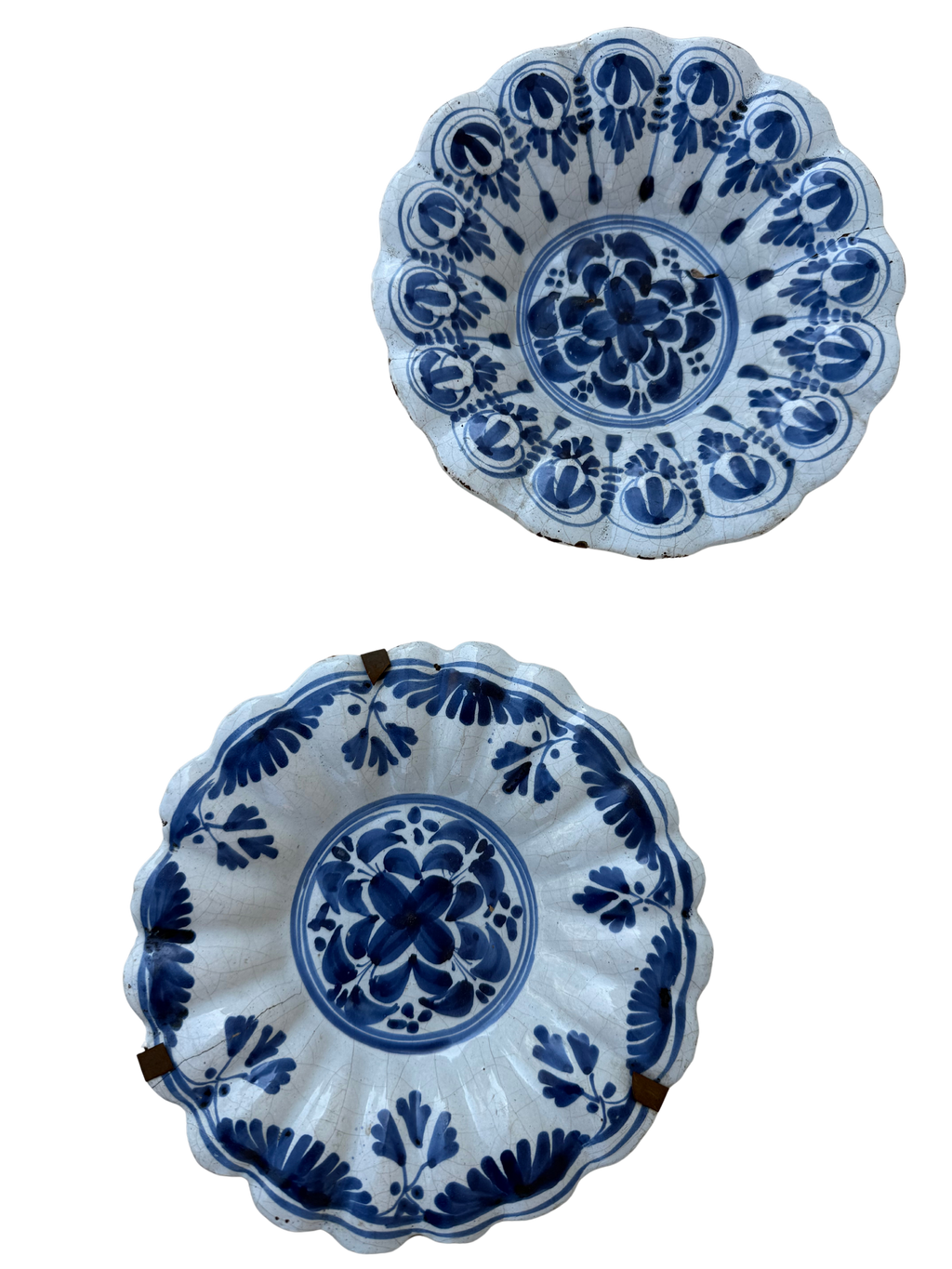 Two blue and white hand-painted ceramic bowls with scalloped edges, displayed against a plain white background.