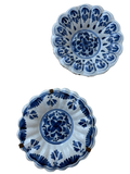 Two blue and white hand-painted ceramic bowls with scalloped edges, displayed against a plain white background.
