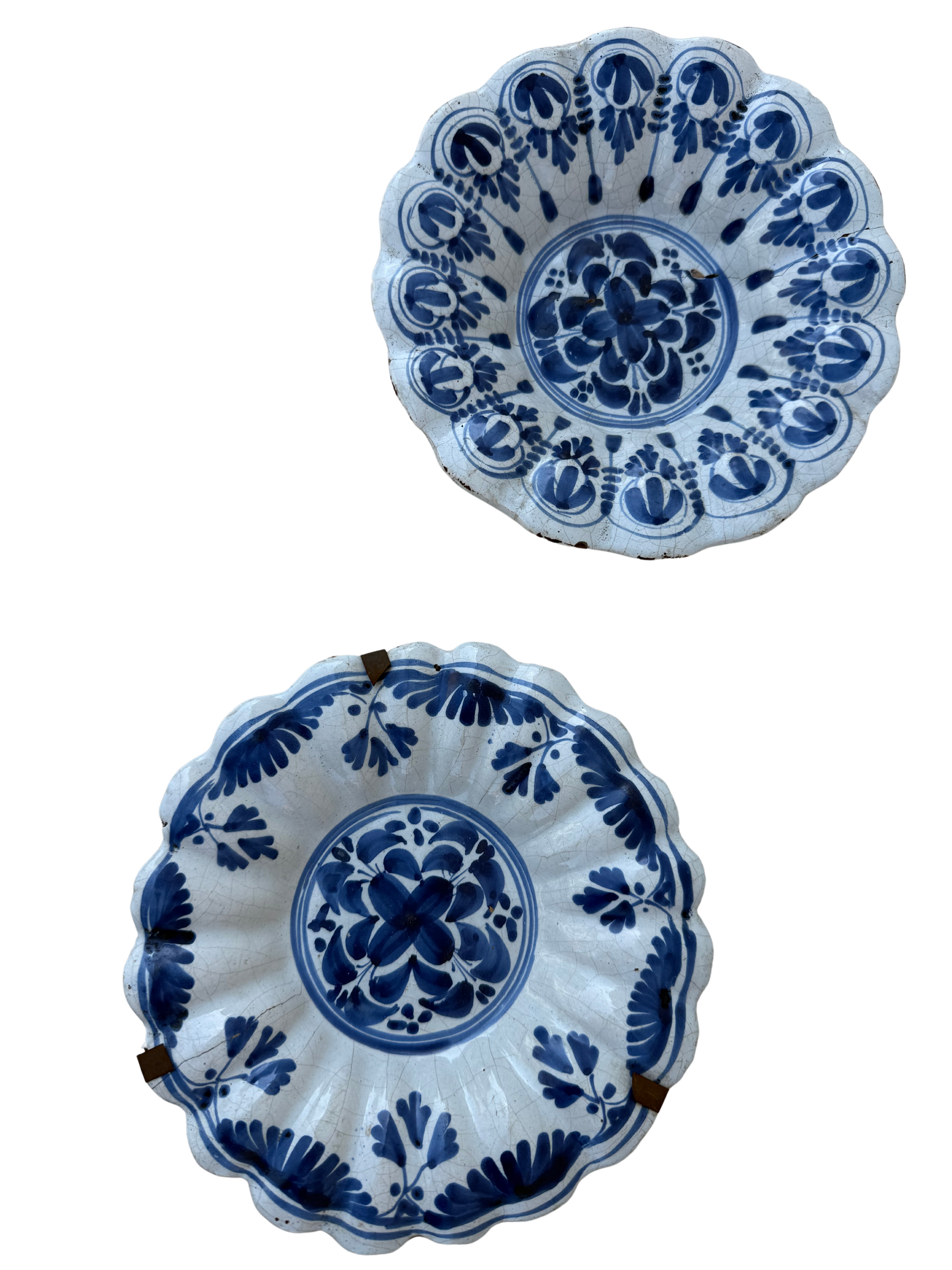 Two blue and white hand-painted ceramic bowls with scalloped edges, displayed against a plain white background.