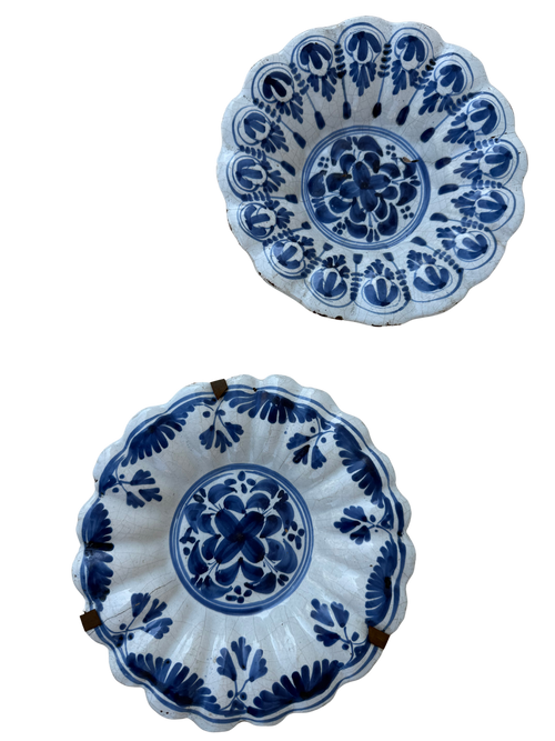 Two blue and white hand-painted ceramic bowls with scalloped edges, displayed against a plain white background.