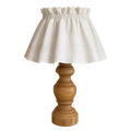A table lamp with a natural beige linen ruffled shade and a turned wooden base, shown against a plain white background.