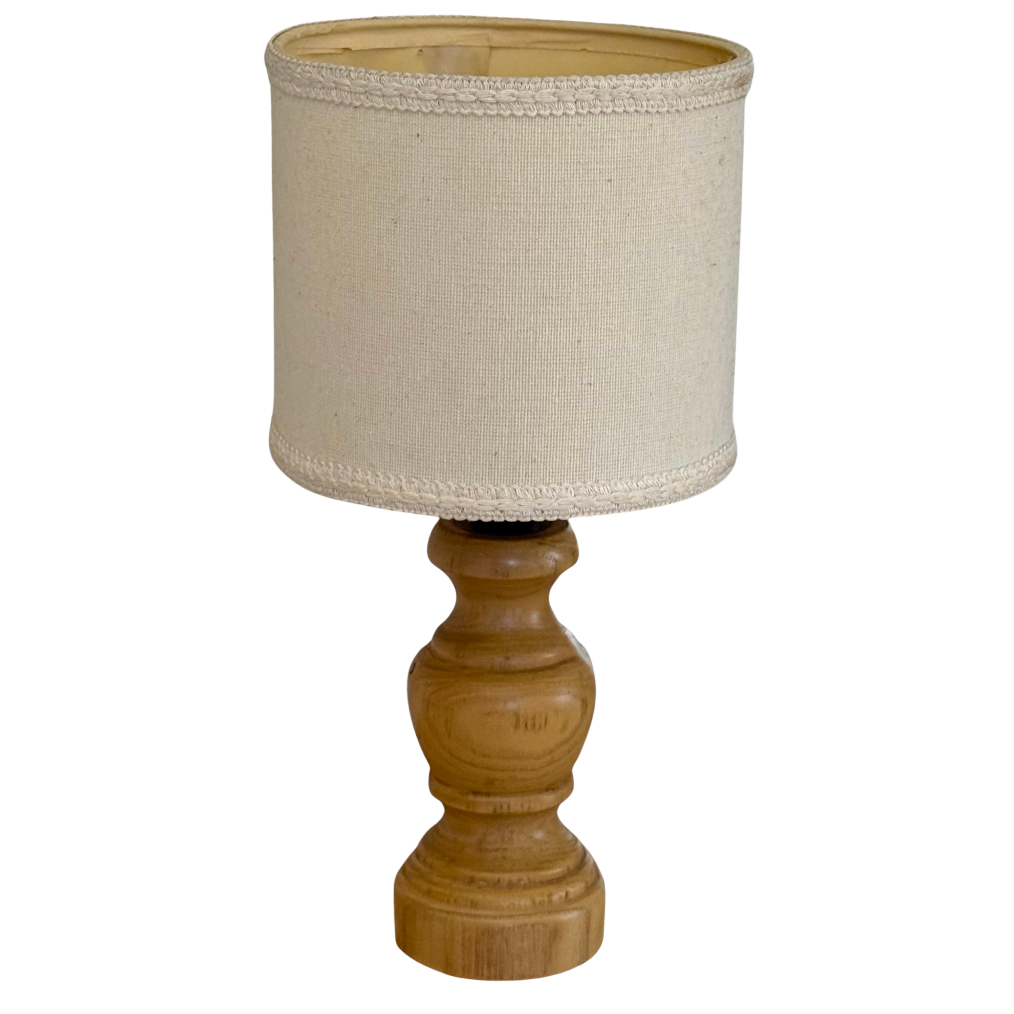 A table lamp with a natural wood turned base and a beige linen drum shade, isolated on a white background.